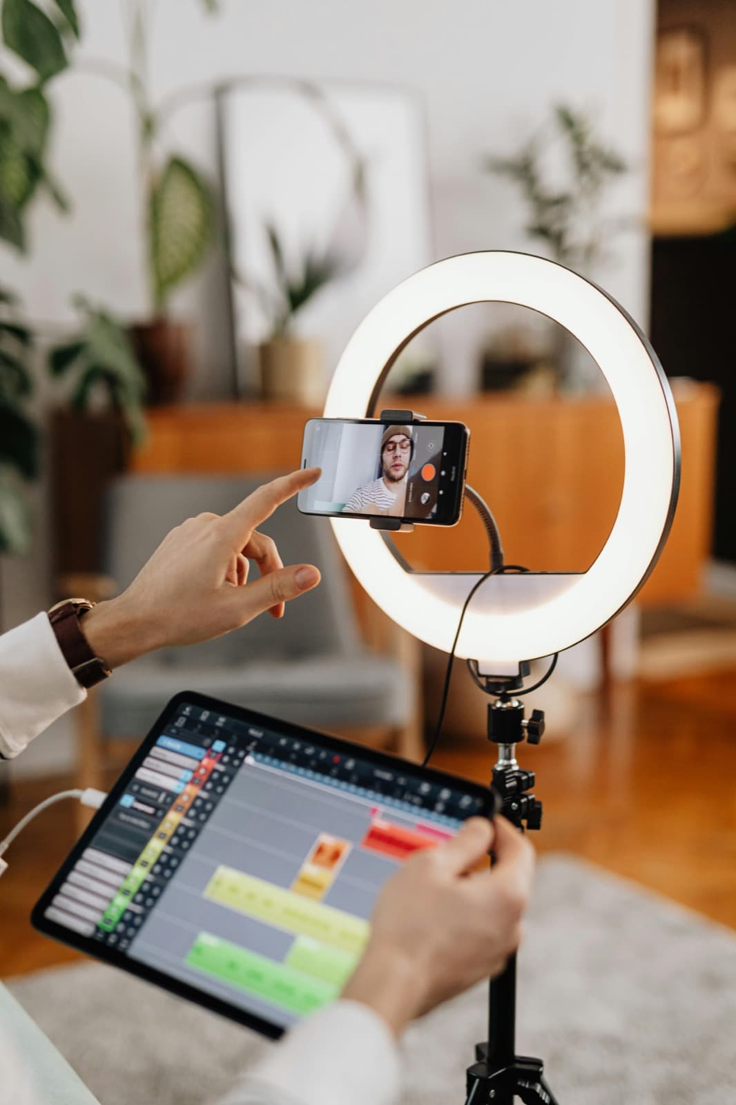 Creator filming a video with a ring light and editing tablet